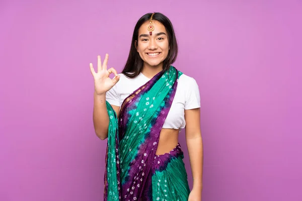 Young Indian woman with sari over isolated background showing ok sign with fingers