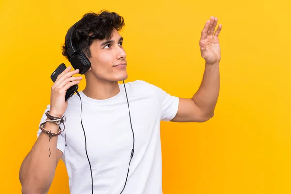 Jovem Argentino Ouvindo Música Com Celular Sobre Uma Parede Amarela — Fotografia de Stock