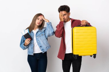 Mavi arka planda bir bavul tutan gezgin çift şaşırmış ve şok olmuş bir yüz ifadesine sahipler.