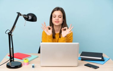 Öğrenci kız, Zen pozisyonunda mavi arka planda izole bir şekilde evinde okuyor.