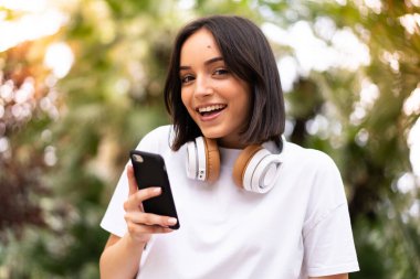 Açık havada telefon kullanan beyaz bir kadın.