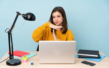 Öğrenci kız, mavi arka planda izole bir şekilde evinde ders çalışıyor.