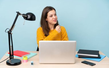 Öğrenci kız evinde çalışıyor. Mavi arka planda tek başına zaferi kutluyor.