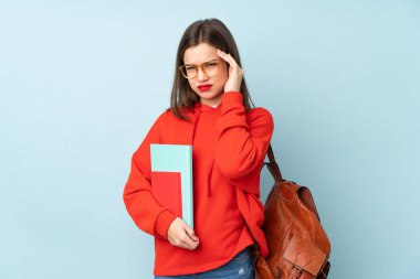 Mavi arka planda izole edilmiş kitapları tutan öğrenci kız mutsuz ve hayal kırıklığına uğramış. Olumsuz yüz ifadesi