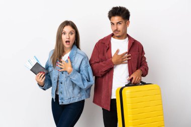 Mavi arka planda izole edilmiş bir bavul taşıyan gezgin çift sağa bakarken şaşırmış ve şok olmuştu.