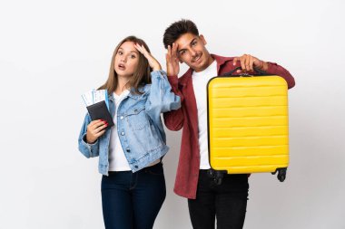 Mavi arka planda izole edilmiş bir bavul taşıyan gezgin çift bir şey fark etti ve çözüme niyetleniyorlar.