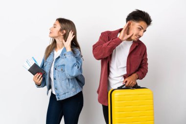 Gezgin çift mavi arka planda izole edilmiş bir bavul tutuyor ve bir şeyler dinliyorlar.