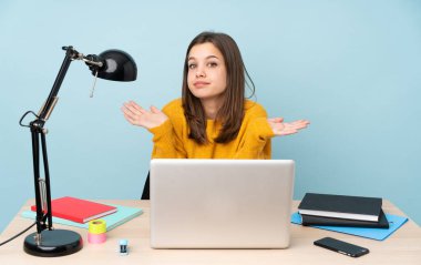 Evinde okuyan öğrenci kız mavi arka planda izole bir şekilde el kaldırırken şüpheye düşüyor.