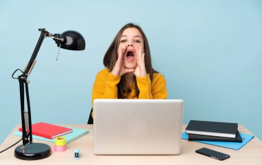 Evinde okuyan öğrenci kız mavi arka planda izole bir şekilde bağırıyor ve bir şeyler söylüyor.