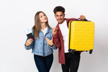 Gezgin çift mavi arka planda izole edilmiş bir bavul taşıyor. Kendini beğenmiş ve gururlu bir aşk konsepti.