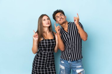Mavi arka planda izole edilmiş genç beyaz çift işaret parmağıyla işaret etmek harika bir fikir.