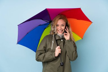 Mavi arka planda şemsiye tutan kadın