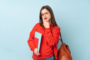 Elinde mavi arka planda kitap tutan öğrenci bir fikir düşünüyor.