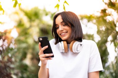 Açık havada telefon kullanan beyaz bir kadın.