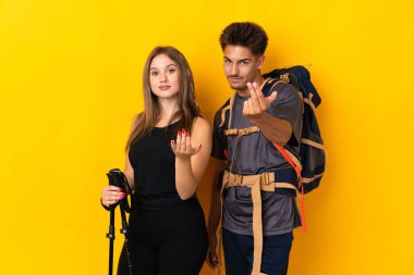 Sarı arka planda izole edilmiş büyük sırt çantalı genç dağcı çift el ele tutuşmaya davet ediyor. Gelmene sevindim.