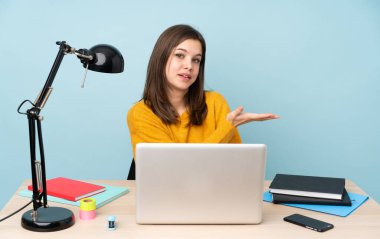 Evinde okuyan öğrenci kız mavi arka planda tek başına bir fikir sunuyor ve gülümsüyor.