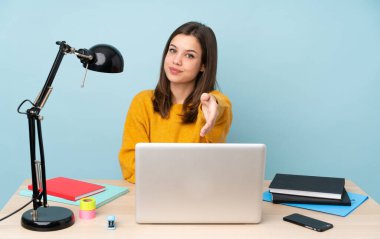 Öğrenci kız, mavi arka planda izole bir şekilde evinde çalışıyor ve iyi bir anlaşma için el sıkışıyor.