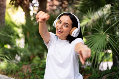 Dışarıdaki kulaklıklı beyaz kadın gülümserken seni işaret ediyor.