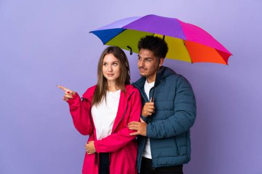 Mavi arka planda bir şemsiye tutan çift gülümseyerek bir fikir sunuyor.