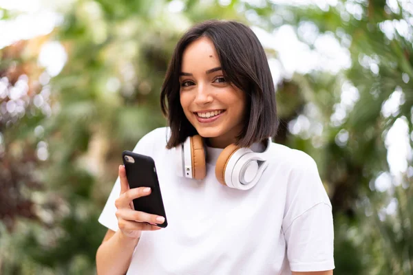 Açık havada telefon kullanan beyaz bir kadın.