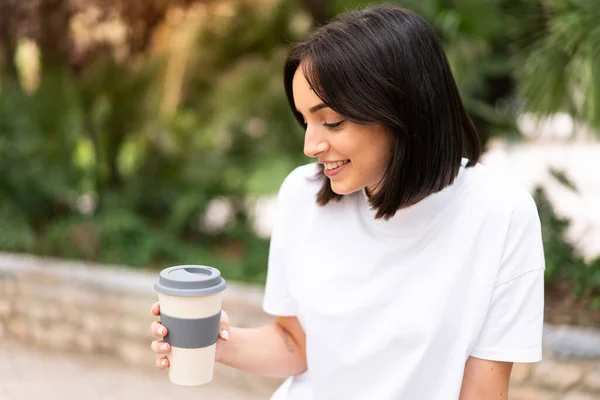 年轻漂亮的女人拿着咖啡到外面去喝 — 图库照片