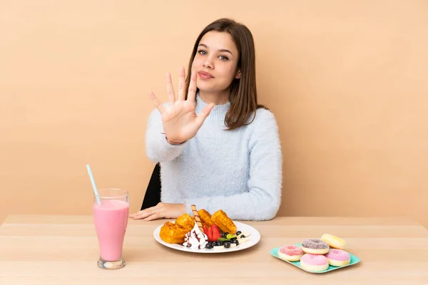 Chica Adolescente Comiendo Gofres Aislados Sobre Fondo Beige Contando Cinco —  Fotos de Stock