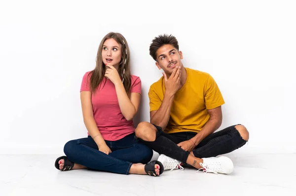 Young Couple Sitting Floor Isolated White Background Looking While Smiling — Stock Photo, Image