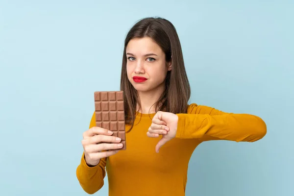 Teenager Girl Isolated Blue Background Taking Chocolate Tablet Making Bad — Stock Photo, Image