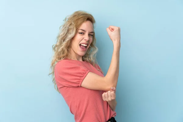 Giovane Donna Bionda Isolata Sfondo Blu Facendo Gesto Forte — Foto Stock