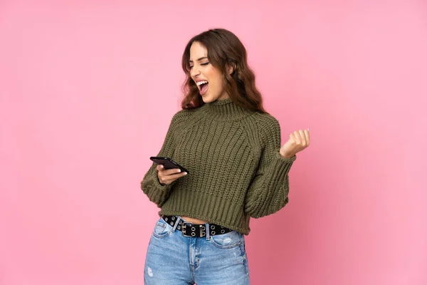 Jovem Mulher Sobre Fundo Rosa Isolado Com Telefone Posição Vitória — Fotografia de Stock