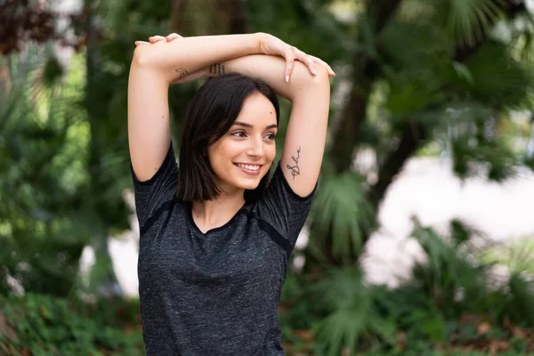 Genç, beyaz bir kadın parkın içinde esniyor.