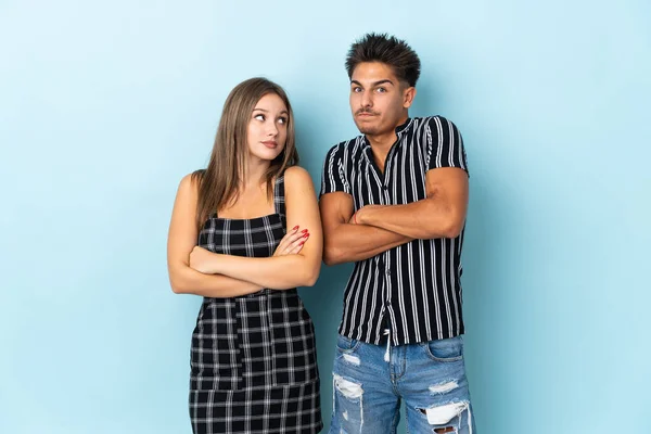 Teenager Caucasian Couple Isolated Blue Background Making Doubts Gesture While — Stock Photo, Image