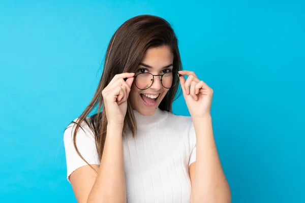 Teenager Mädchen Über Isolierten Blauen Hintergrund Mit Brille Und Überrascht — Stockfoto