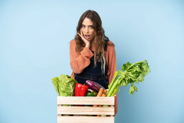 Farmer with freshly picked vegetables in a box surprised and shocked while looking right