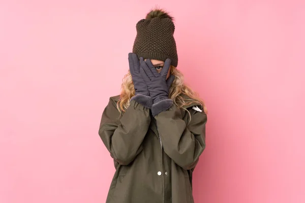 戴着冬帽的小女孩被粉色背景遮住眼睛 用手指看着 — 图库照片