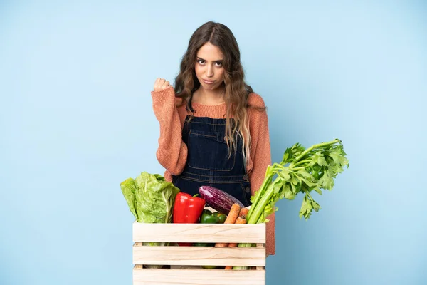 Farmer with freshly picked vegetables in a box with angry gesture