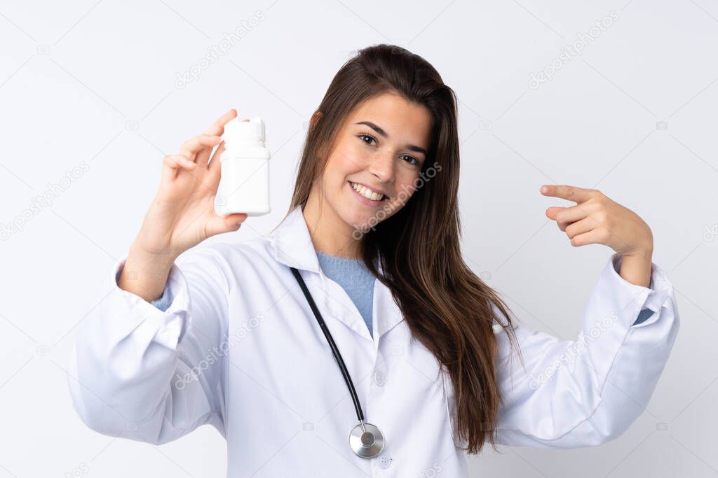 Teenager girl over isolated white background wearing a doctor gown and holding pills