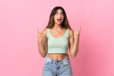 Pembe arka planda izole edilmiş genç beyaz kadın şaşırmış ve yukarı bakıyor.