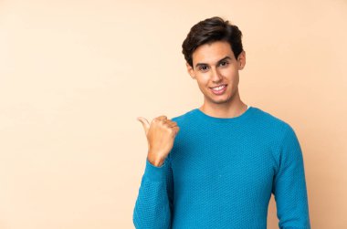 İzole edilmiş arka plandaki adam bir ürünü sunmak için kenarı işaret ediyor.