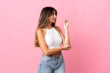 Pembe arka planda izole edilmiş beyaz bir kadın harika bir fikre işaret ediyor.