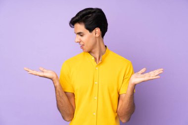 İzole edilmiş mor arkaplan üzerinde iki elle kopyalama alanı tutan adam