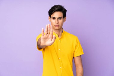 İzole edilmiş mor arka plandaki adam dur hareketi yapıyor.