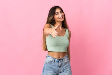 Pembe arka planda izole edilmiş beyaz bir kadın iyi bir anlaşma için el sıkışıyor.