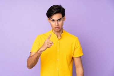 İzole edilmiş mor arka plandaki adam hayal kırıklığına uğramış ve ön tarafı işaret ediyor.