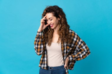 Mavi arka planda izole edilmiş genç beyaz kadın gülüyor.