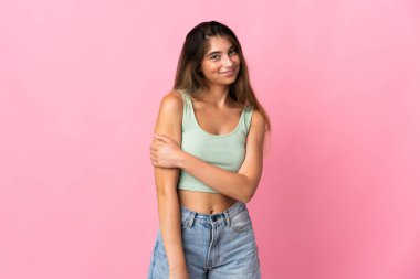 Pembe arka planda izole edilmiş genç beyaz kadın gülüyor.