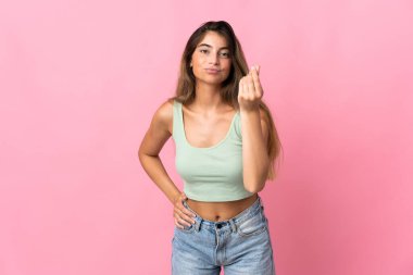 Pembe arka planda izole edilmiş beyaz bir kadın İtalyan jesti yapıyor.
