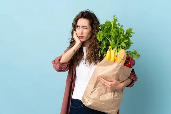 Jonge Vrouw Met Een Boodschappentas Geïsoleerd Blauwe Achtergrond Gefrustreerd Het — Stockfoto