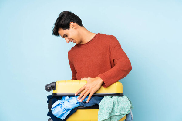 Man with a suitcase full of clothes over isolated blue background