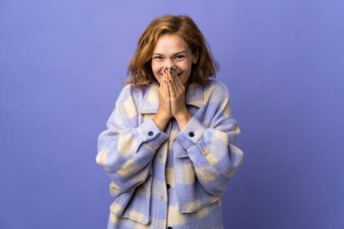 Genç Gürcü kadın mor arka planda izole edilmiş mutlu ve gülümseyen elleri ile ağzını kapatıyor.